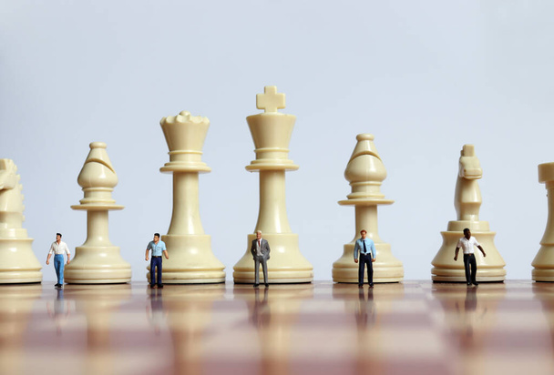 Las piezas de ajedrez y las personas en miniatura en el tablero de ajedrez
. - Foto, imagen