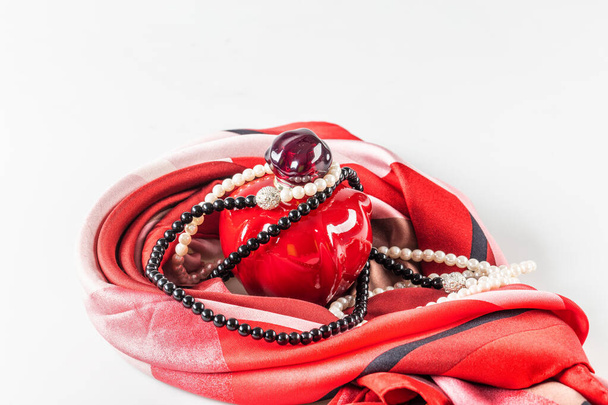 Нові жіночі парфуми, намисто з перлами, шовковий шарф на білому тлі крупним планом
. - Фото, зображення