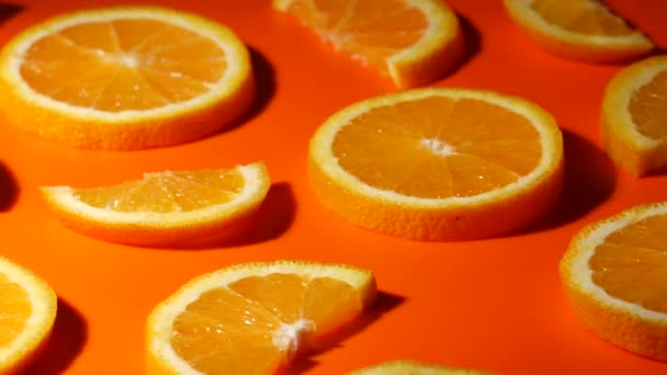 Kleurrijk fruitpatroon van sinaasappelschijfjes op oranje achtergrond. Bovenaanzicht. - Video