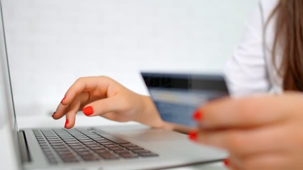 Nainen tekee ostoksia luottokortilla verkossa kannettavan kotona. Kädet, luottokortti ja sormet näppäimistöllä lähikuva - Materiaali, video