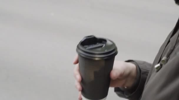 Close-up van vrouwelijke hand met take-away koffie tijdens het wandelen in de stad.  - Video