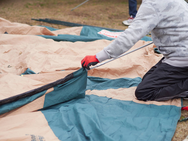 Японский мужчина расставляет палатку
. - Фото, изображение