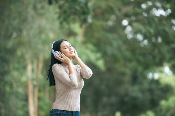 Asiatin hört Lieblingsmusik über Kopfhörer. Glückliche Zeit und Entspannung. - Foto, Bild