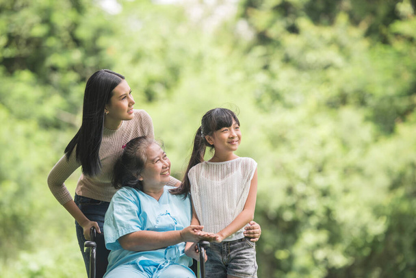Glückliche Großmutter im Rollstuhl mit Tochter und Enkelkind im Park, Glückliches Leben Glückliche Zeit. - Foto, Bild