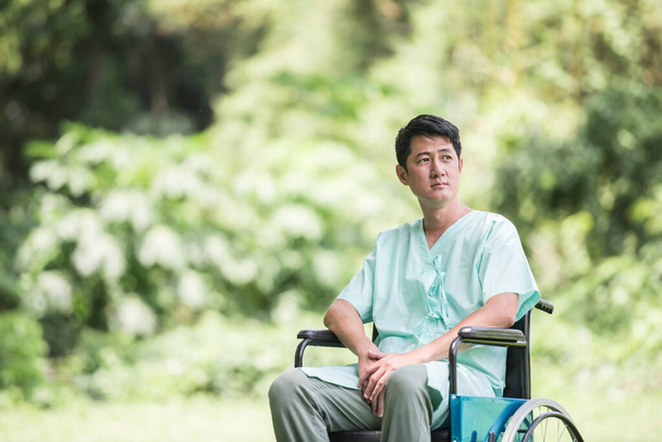 Один молодий інвалідний чоловік у інвалідному візку в саду
 - Фото, зображення
