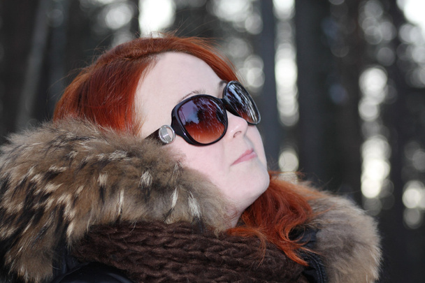 Happy girl in warm clothes and sunglasses looks away in forest a - Fotó, kép