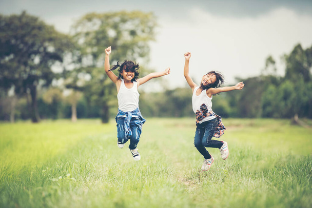Две маленькие девочки счастливый прыжок в природный парк
 - Фото, изображение