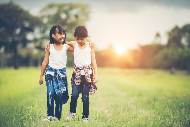 Дві маленькі дівчата рука тримається разом розважатися в парку
 - Фото, зображення