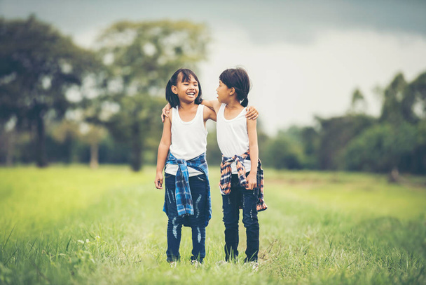 二人の女の子が手を携えて一緒に公園で楽しみを持って - 写真・画像