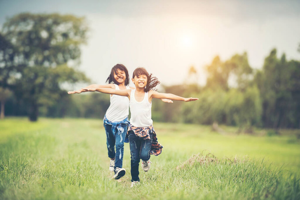 Deux petites filles mignonnes courent sur l'herbe verte. Meilleurs amis. - Photo, image
