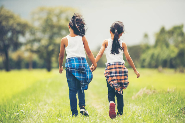Two little girls hand holding together having fun in the park - Photo, image