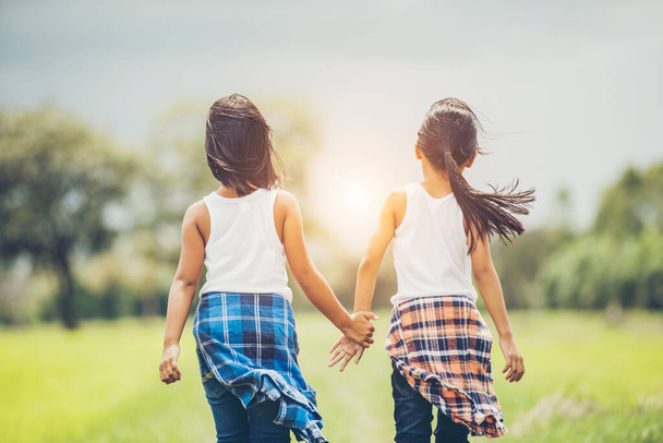 Dwie małe dziewczynki trzymają się razem i bawią się w parku - Zdjęcie, obraz