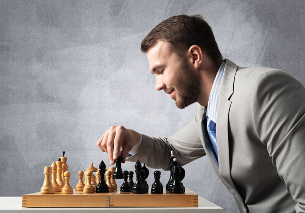 Concentrated businessman playing chess game - Photo, image