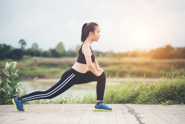 Mujer joven saludable calentando ejercicio al aire libre antes de la sesión de entrenamiento en el parque
. - Foto, Imagen