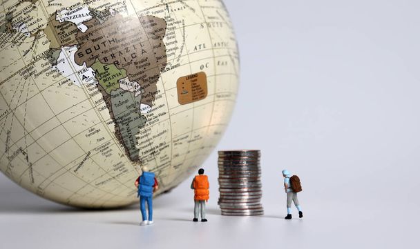 Μινιατούρες τουρίστες με σωρούς από κέρματα μπροστά από τον κόσμο. - Φωτογραφία, εικόνα