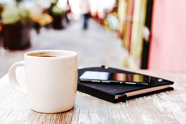 xícara de café e telefone inteligente ao ar livre em uma mesa no café ou café com fundo borrado
 - Foto, Imagem