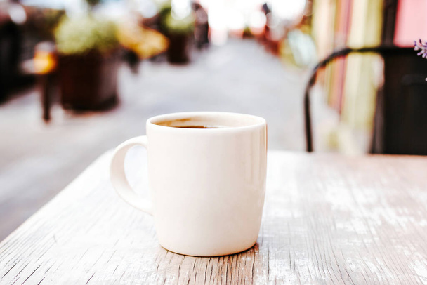 kopje koffie in de straat of buiten in een koffiehuis of café met wazige achtergrond - Foto, afbeelding