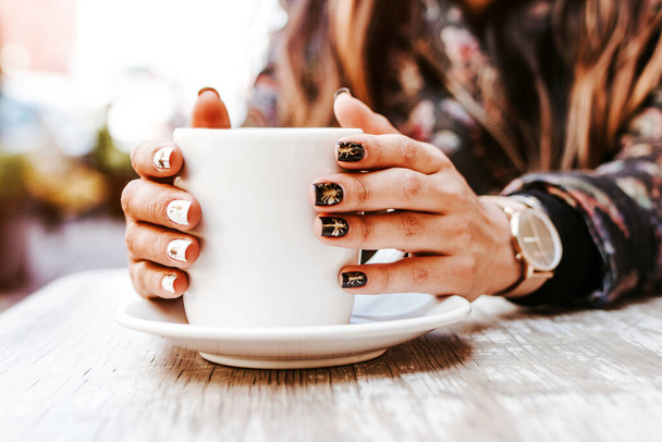 woman hand holding a cup of coffee outdoors at coffee shop or cafe with blurred background - Foto, Imagem