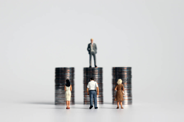 Miniaturmenschen mit Haufen von Münzen. Ein Konzept zum Konflikt zwischen Arbeitgebern und Arbeitnehmern. - Foto, Bild