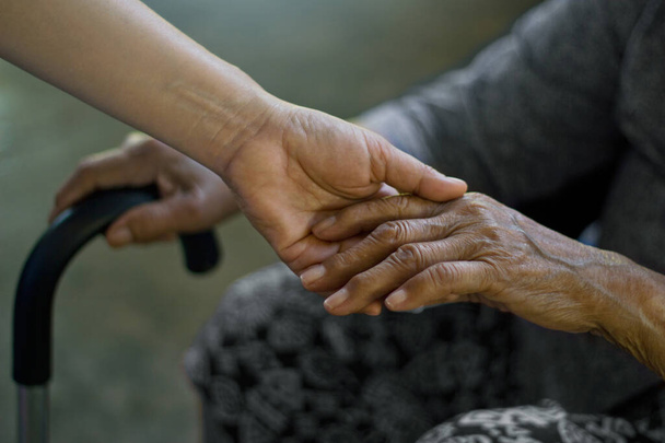 Córka trzymająca za rękę matkę w podeszłym wieku cierpiącą na chorobę Alzheimera i Parkinsona, utrata pamięci spowodowana demencją. - Zdjęcie, obraz