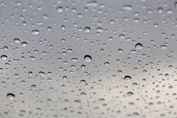 Gota de água de perto. Gotas de água na superfície de vidro como fundo. Gotas de chuva em vidro. Fundo do céu. Tailândia
. - Foto, Imagem