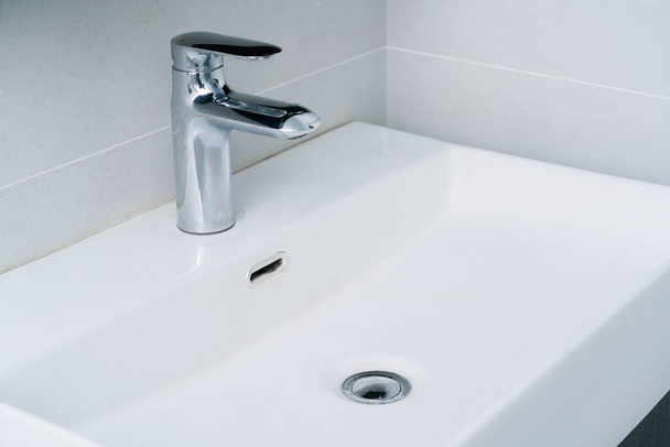 Handwasbak en kraan van minimalistisch huishoudelijk toilet - Foto, afbeelding