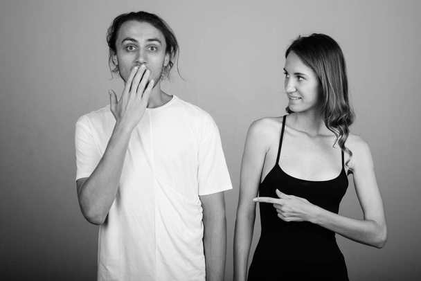 Estúdio tiro de jovem bonito homem e jovem bela mulher juntos contra fundo cinza em preto e branco - Foto, Imagem