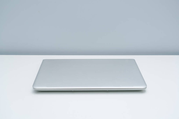 Gümüş rengi gri dizüstü bilgisayar beyaz masaya yerleştirildi - Fotoğraf, Görsel