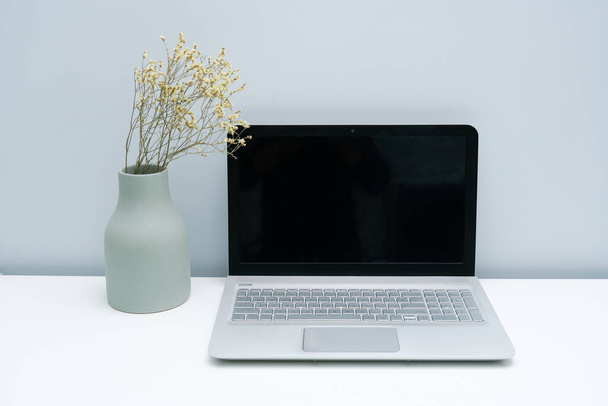 Ваза і ноутбук на білій стільниці
 - Фото, зображення