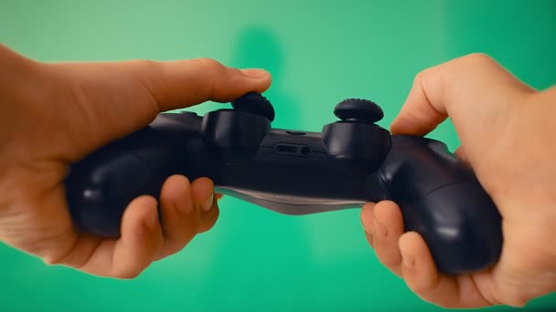 緑の画面と大きなフラットスクリーンの反対側のプレイヤーの手の中にゲームパッド, 4k - 映像、動画