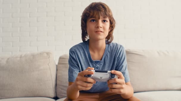 A young pre-teenage boy is playing video game console, have fun, laugh, hold the joystick, 4k - Footage, Video