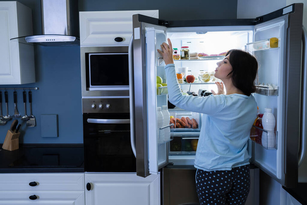 Nälkäinen nainen yöllä auki jääkaappi - Valokuva, kuva