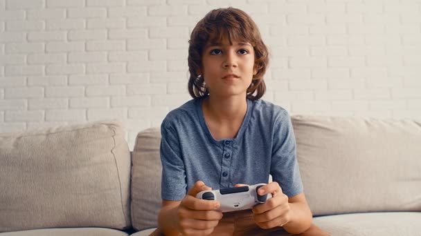 A young pre-teenage boy is playing video game console, have fun, laugh, hold the joystick, 4k - Footage, Video