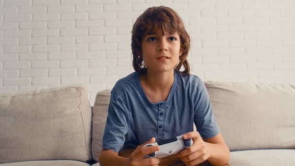 Un joven pre-adolescente está jugando videoconsola, divertirse, reír, sostener el joystick, 4k
 - Metraje, vídeo