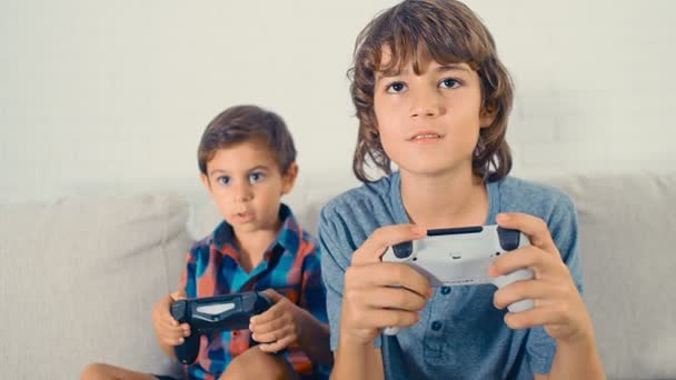 Два мальчика играют в приставку видеоигры, веселятся, смеются, держат джойстик, празднуя победу, 4k
 - Кадры, видео