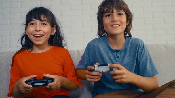 Młody, nastoletni chłopiec i dziewczyna grają w konsolę do gier wideo, bawią się, śmieją, trzymają joysticka, świętują zwycięstwo, 4k - Materiał filmowy, wideo
