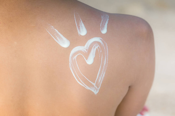 Beauty Attractive Asian young woman  smile with healthy skin applying sunscreen lotion Heart shape on her shoulder on the beach for UV protection,Skin care Concept - Φωτογραφία, εικόνα