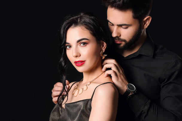 Young couple wearing stylish accessories on dark background - Фото, изображение