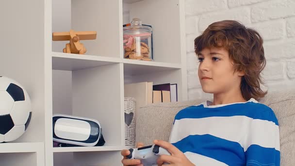 Un jeune garçon pré-adolescent joue à la console de jeux vidéo, amusez-vous, riez, tenez le joystick, 4k - Séquence, vidéo