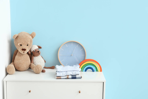 Toys with clothes and clock on chest of drawers in room - Foto, Imagen