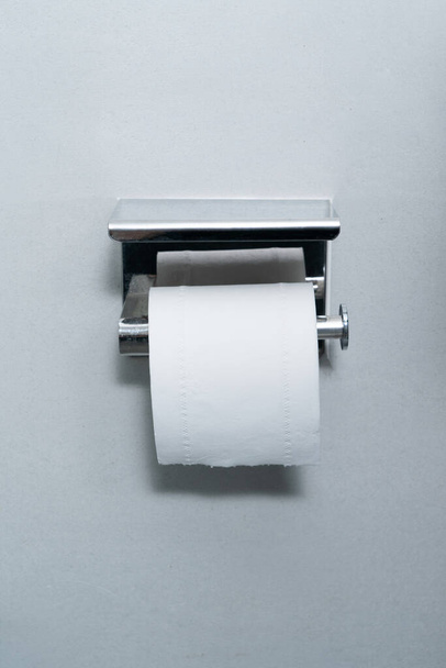 Role toaletního papíru na šedé stěně. - Fotografie, Obrázek