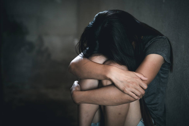 Молодая депрессивная женщина, домашнее насилие и изнасилование, избитая и изнасилованная сидя в углу, скопируйте пространство. Международный женский день - Фото, изображение