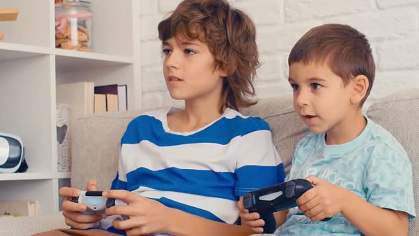 Dwóch chłopców gra w konsolę do gier wideo, baw się dobrze, śmiej się, trzymaj joysticka, świętuj zwycięstwo, 4k - Materiał filmowy, wideo