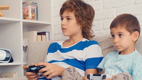 Two boys playing video game console, have fun, laugh, hold the joystick, celebrating victory, 4k - Filmati, video