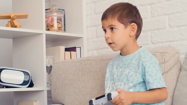 5χρονο αγόρι που παίζει κονσόλα βιντεοπαιχνιδιών, διασκεδάζει, γελάει, κρατάει το χειριστήριο στο σπίτι, 4k - Πλάνα, βίντεο