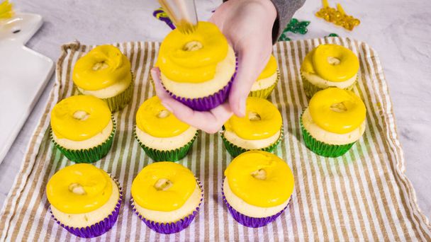 Stap voor stap. Frosting vanille cupcakes met Italiaanse boterroom glazuur voor Mardi Gras viering. - Foto, afbeelding