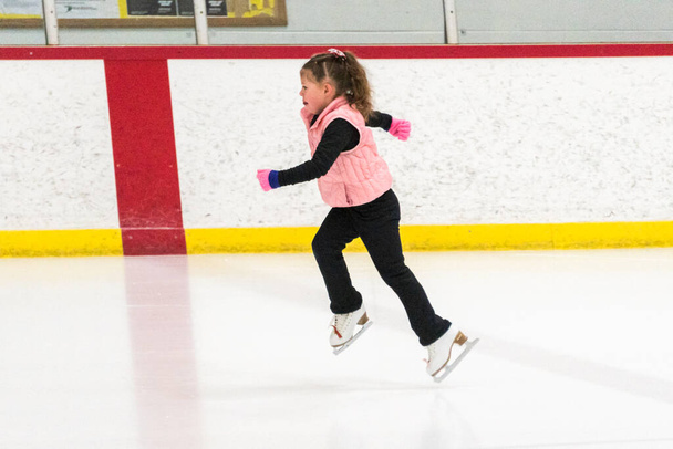 Kleine schaatsster oefent haar elementen in de ochtend kunstschaatstraining. - Foto, afbeelding