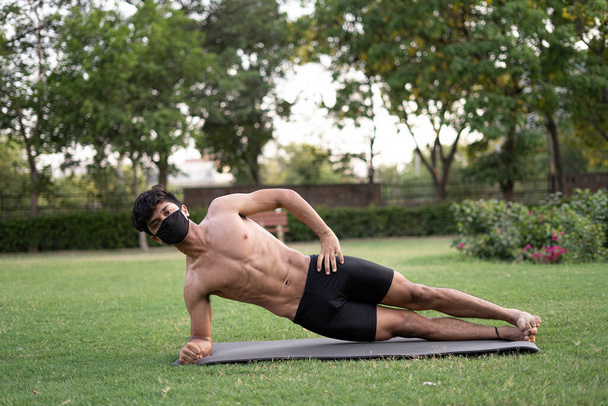 Een jonge indiaanse versnipperde tiener jongen doet yoga aasan in het park op internationale yoga dag - Foto, afbeelding