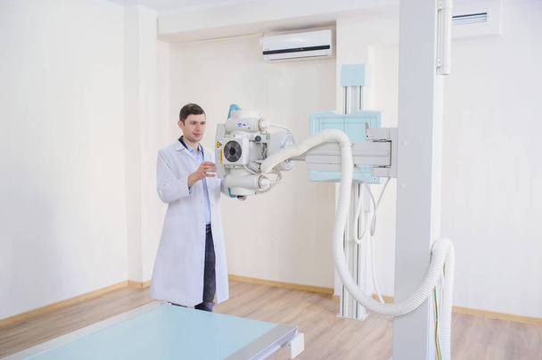  widok boczny męskiego radiologa dostosowującego aparat rentgenowski w badaniu rom - Zdjęcie, obraz