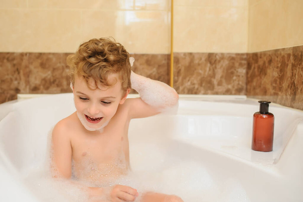 Menino lavando e brincando na banheira com espuma e bolhas de sabão
 - Foto, Imagem